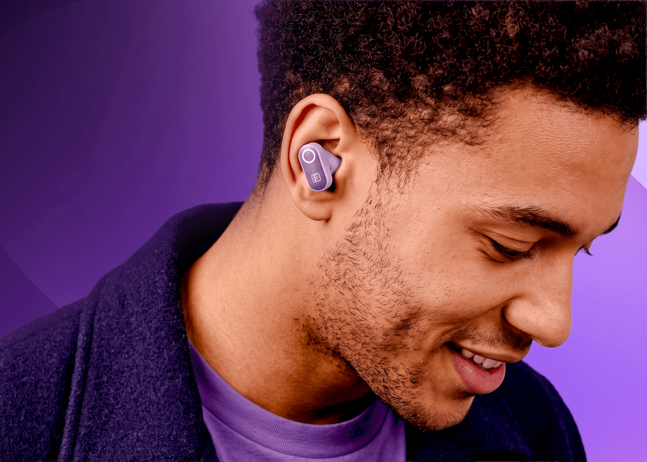A close-up of a man wearing a purple in-ear wireless earbud, shown in profile against a purple background.